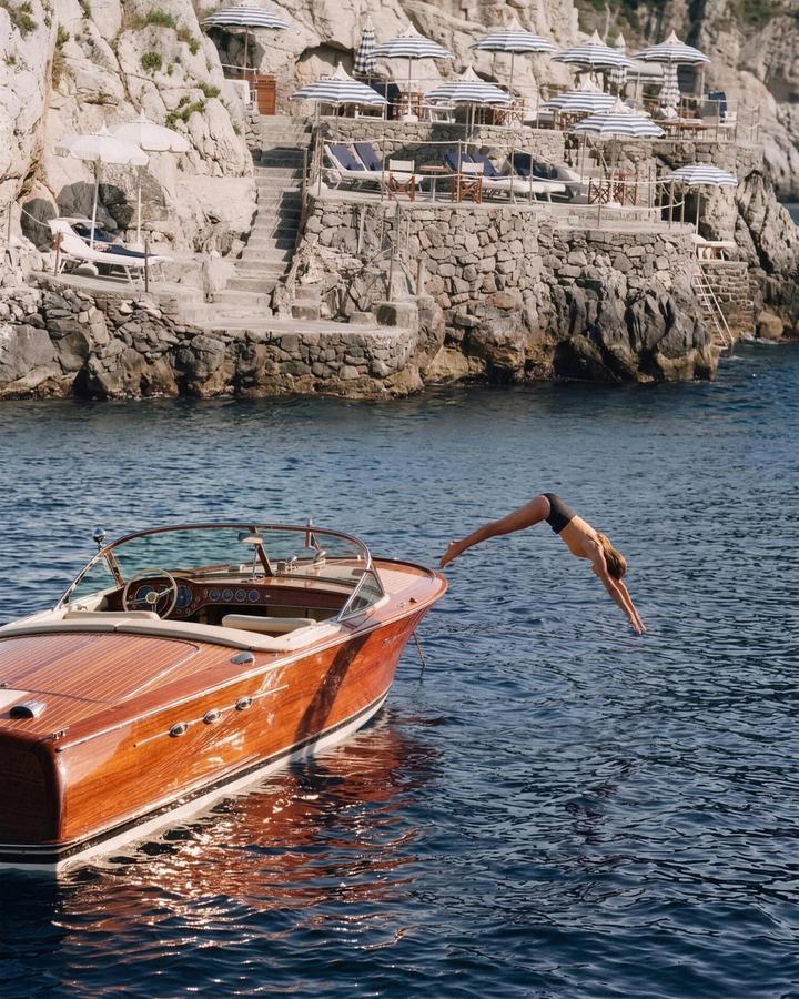 Diving off a varnished launch below the beach club